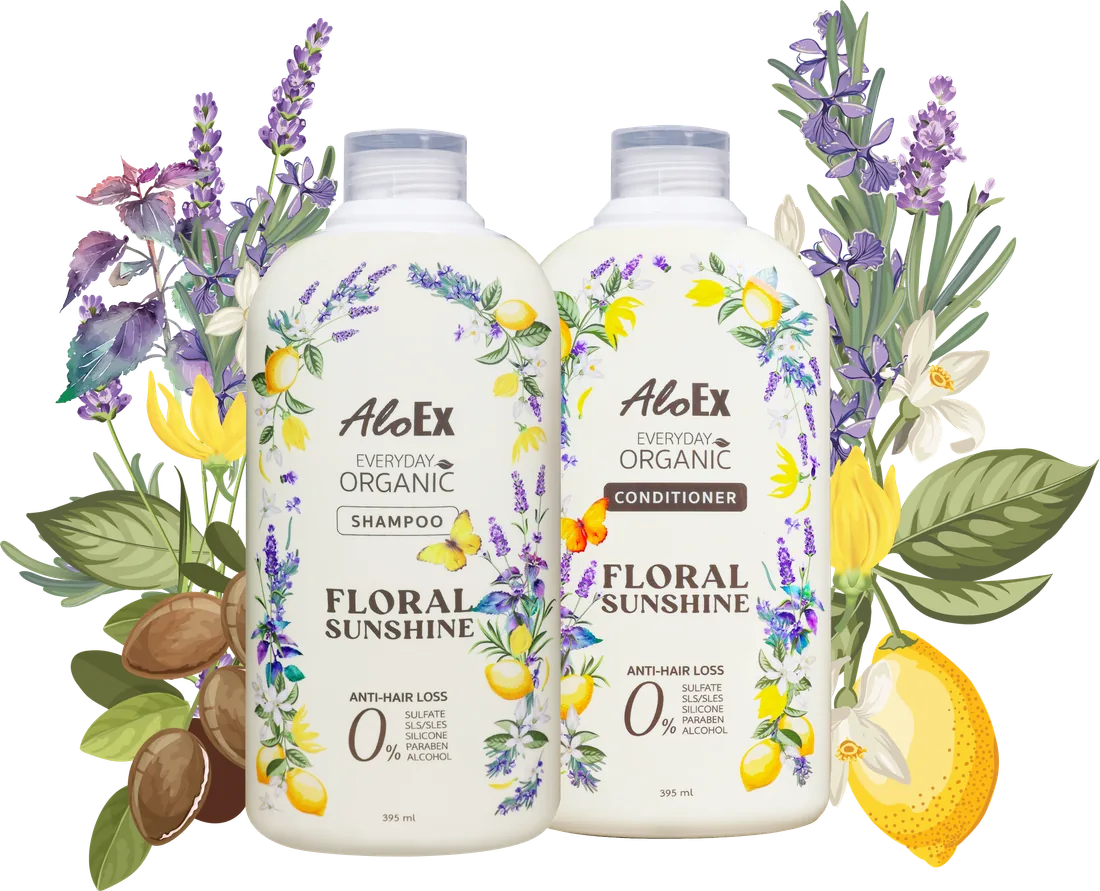 AloEx Everyday Organic Floral Sunshine shampoo and conditioner bottles side by side, framed by lavender, ylang-ylang, lemon and argan nuts